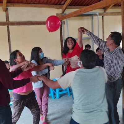 Men and women join hands to bounce a red balloon into the air